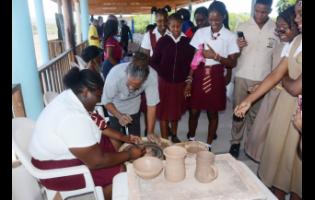 Master potter Phillip Supersad guides Newell High School student, Ashantie Graham, in a pottery-making lesson while other students observe, during the recent Tourism Product Development Company Limited Youth Expo and Career Fair at the Breds Treasure Beach Sports Park in St Elizabeth.