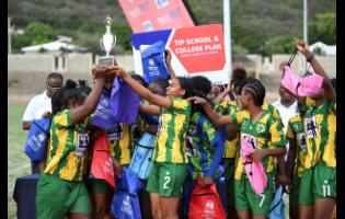 Excelsior High’s players celebrate with the championship trophy after defeating Holmwood Technical High 9-1 in the ISSA/Tip Friendly Society schoolgirls football final at the Stadium East field yesterday.