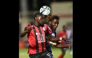 Rushane Thompson (left) of Arnett Gardens battles with Portmore United’s Akeem Mullings during Monday  night’s Jamaica Premier League playoff game at Sabina Park. The game ended in a 1-1 draw.