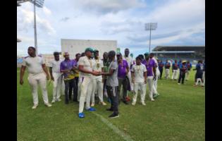 Kingston Cricket Club’s captain Akim Fraser (foreground left) and coach Terrence Corke enjoy the limelight of holding the JCA Senior Cup while other players and officials watch after the final at Sabina Park yesterday.