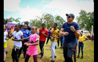 Minister of Health and Wellness, Dr Christopher Tufton, goes through several exercise routines with students participating in last Friday’s National School Moves Day event at Manchester High School, in Mandeville. 