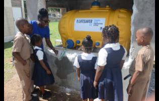 Contributed 
Acting Principal of New Hope Primary School in Westmoreland, Latoya Green-Ruddock, explaining the features of a new water purification system that was installed at the institution to students. 