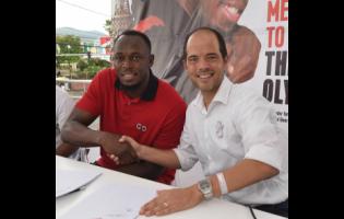 Olympic Games and World Championships gold medallist Usain Bolt (left) shakes hands with Red Stripe’s Managing Director Daaf Van Tilburg shortly after a signing ceremony for Bolt to be a brand ambassador for Red Stripe during the launch of Red Stripe’s ‘Guh Fi Gold and Glory’ campaign at the Half-Way Tree Transport Centre yesterday.