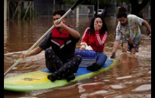 People evacuate on a surfboard from a neighbourhood flooded by heavy rains on Saturday in Canoas, Rio Grande do Sul state, Brazil.