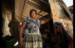 Sandra Shepherd stands at the entrance of the wooden structure, covered with tarpaulin, that has called home for months.