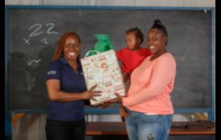 Karen McGlashin (left), social worker at Project STAR, presents Shanakay Powell with a gift at a parent club session recently.