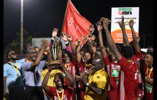 Boys’ Town’s players  celebrating with the KSAFA Championship League trophy after defeating the Jamaica Defence Force 6-5 on penalties at the Anthony Spaulding Sports Complex last night.  