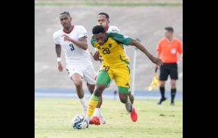 Jamaica’s Renaldo Cephas shields the ball from  Dominican Republic’s Ronaldo Vasquez while his teammate Junior Firpo (left) looks on. The action is from yesterday’s 2026 World Cup qualifying match at the National Stadium. Jamaica won 1-0.