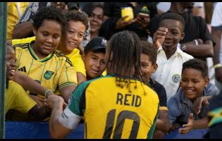 Reggae Boyz midfielder Bobby Decordova-Reid greets some young fans at the National Stadium yesterday after Jamaica defeated the Dominican Republic 1-0 in a 2026 World Cup qualifying match. 