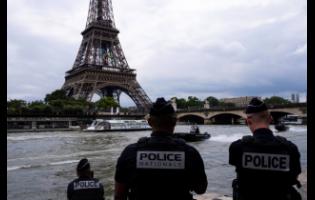 Police officers watch river police boats patrolling past the Eiffel Tower on Tuesday, July 2, on the Seine river in Paris. The river will host the Paris 2024 Olympic Games opening ceremony on July 26 with boats for each national delegation. 