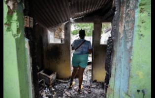 Shakira Murray looks on at the charred remains of her home on Harris Street in Rose Town, Kingston. Murray also suffered loss due to fire in October 2023 and will have to start over again.