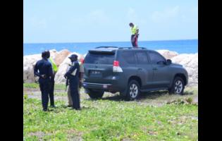 Police personnel process a crime scene on the Palisadoes road in Kingston where a soldier is believed to have committed suicide.