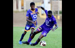 Kingston College’s Deshawn Byfield (right)dribbles the ball under pressure from Cumberland High School’s Rashard Farrington (right) during the ISSA/WATA Manning Cup football match at Stadium East on Saturday. KC won 18-0.