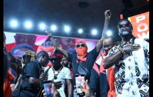 Vybz Kartel (centre) raises his clenched fists in a show of support for the People’s National Party at its annual conference held at the National Arena yesterday.