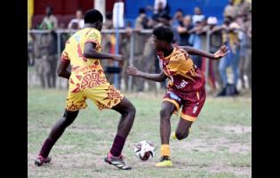 Wolmer’s Boys’ Davaughn Ricketts looks on while Denham Town’s Odeano Porteous attempts some tricks during their ISSA/WATA Manning Cup football encounter at St Andrew Technical High School on Friday.