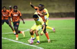 Mario Simms (centre) of Waterhouse FC  tries to keep the ball away from Tkiven Garnett (second right) of Tivoli Gardens and his teammates during the Jamaica Premier League football match at Stadium East yesterday. Tivoli won 2-1.