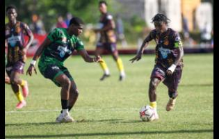 Kevin Hall (right) of St Andrew Technical High School (STATHS) dribbles the ball, while Keneal Peters of Calabar High looks to defend during the ISSA WATA Manning Cup football match, at Stadium East on Tuesday. STATHS won 4-1.