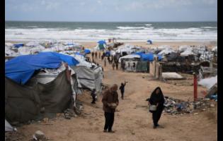 Palestinians receive donated food at a temporary camp for displaced people, on the beach near the port of Gaza City, on Sunday.