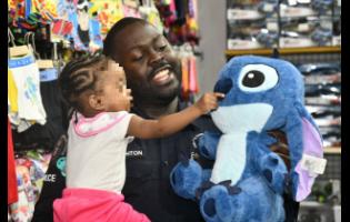 Superintendent of Police Throyville Haughton, attached to the St Catherine South Police Division, shares a warm moment with an infant as he presents her with a stuffed toy during the ‘Shop with a Cop’ initiative, held on December 19 at Portmore Pines Plaza in St Catherine.