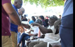 Mayor of Kingston Andrew Swaby delivers food to persons at Thursday’s treat at St William Grant Park. 