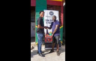 Janoi Cunningham (left), Worthy Park’s trade developer, hands over a generator to Aubrey Stone, of Stone’s Fruits & Bar, in Oxford, St Elizabeth.
