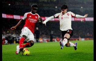 Liverpool’s Milos Kerkez extends himself in an effort to block Arsenal’s Buyako Saka (left) during the English Premier League soccer match at Emirates Stadium in London, England, on Thursday, January 8, 2025.