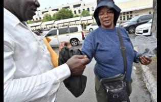 A customer collects his bag from Simone ‘Shelly’ Henry, who keeps phones and bags safe outside the US Embassy in Kingston.