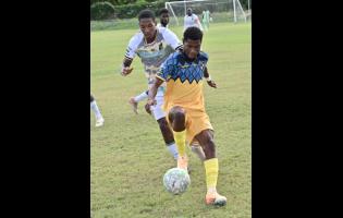 Racing United’s Tajay Ajani (right) controls the ball while under pressure from Treasure Beach’s Daniel Hardy during a Jamaica Premier League football match at the Ferdi Neita Park yesterday. Racing won 4-1.
