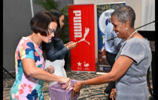 Simone Foote (left), marketing manager of BPM Financial Ltd, and Genevieve Reid prepare the pot for sponsors to draw events during the launch of the Gibson McCook Relays at The Jamaica Pegasus hotel in New Kingston yesterday.