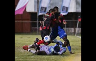 Credit: Ricardo Makyn/Chief Photo Editor Dunbeholden FC goalkeeper Jean-Luke Wilmott pushes away the ball in a tussle involving his teammate Christopher Matthews (right) and Arnett Gardens FC’s Jamone Shepherd during the Jamaica Premier League football match at the Anthony Spaulding Sports Complex on Monday night.