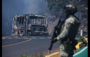 A soldier stands guard by a charred vehicle after it was set on fire, in Cointzio, Michoacán state, Mexico, on Sunday, February 22, following the death of the leader of the Jalisco New Generation Cartel, Nemesio Oseguera, known as “El Mencho”.