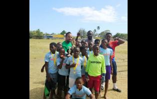 Spanish Town Primary School’s principal, Roogae Kirlew (left, back row), coach Neriah Barrett (centre, back row) and assistant coach (right, back row) celebrate with the players after their 1-0 win over Old Harbour Primary in the Insports St Catherine Primary Schools’ football final. Spanish Town won 1-0.