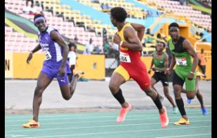 Mark-Daniel Allen (second left) of Wolmer’s Boys’ glances at Kingston College’s Brandon Bennett (left) as he powers to the line to win the boys’ Under-17 110 metres hurdles in 13.57 seconds at the Carifta Trials yesterday.