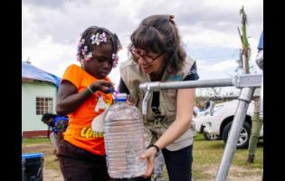 Olga Isaza, UNICEF representative, helps a child at a water station.