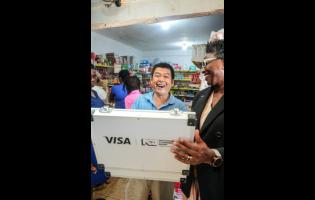 Credit: Contributed Danielle Cameron-Duncan (right), acting senior vice president for payments and channels at NCB, presents Zewei Zheng, owner of San San Haberdashery in St Ann’s Bay, with his $1 million second-place prize from the NCB Business Boost initiative. Zheng used the money to purchase food supplies for hurricane-affected families in his community.