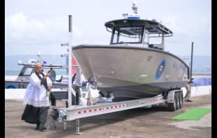 Acting Force Chaplain, Reverend Major Dwayne Blackwood, invokes blessings upon one of the newly acquired high-speed surface interceptor vessels during a blessing ceremony at the Jamaica Defence Force Coast Guard, Port Royal, Kingston, yesterday.