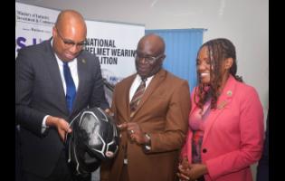 State Minister in the Ministry of Industry, Investment and Commerce, Delano Seiveright (left), Executive Director of the Bureau of Standards Jamaica (BSJ), Dr Velton Gooden, and CEO of the CARICOM Regional Organization for Standards and Quality, Dr Sharonmae Smith Walker, examine a helmet at the recent launch of the BSJ Motorcycle Helmet Standard in Kingston.