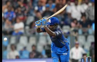 Mumbai Indians’ West Indian batsman Shefane Rutherford hits a boundary during the Indian Premier League cricket match between Mumbai Indians and Royal Challengers Bengaluru, in Mumbai , India, yesterday. Rutherford hit nine sixes in an unbeaten 31-ball 71.