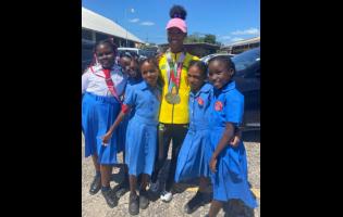 Foga Road High’s Shameika McLean (pink cap) with students from her former school, May Pen Primary, during a parade through the streets of the parish capital yesterday to celebrate the achievements of  Foga Road’s athletes at the ISSA/GraceKennedy Boys and Girls’ Athletics Championships and the recent Carifta Games.