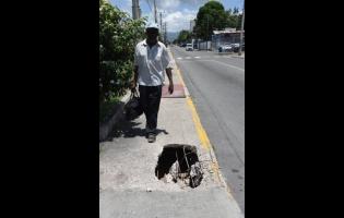 An elderly man is seen navigating a stretch of Marescaux Road in Kingston where a collapsed sidewalk poses a danger to those on foot.