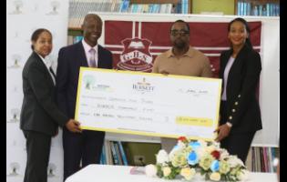 Howard Edwards (second left), acting principal, Glenmuir High School, collects  a cheque valued at US$100,000 from Dale Burnett of Burnett Charitable Fund in partnership with the National Education Trust. They are joined by Rhoda Moy Crawford (right), minister of state, Ministry of Education, Youth, Skills and Information; and Keisha Johnson, director, donor and partnership management at the National Education Trust. The presentation was made during a ceremony held at the school on Monday. 