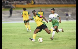 Jamaica’s Khadija Shaw strikes at goal during a Concacaf W Qualifier against Guyana at the National Stadium on Saturday night. Chasing back is Guyana’s Otesha Charles.