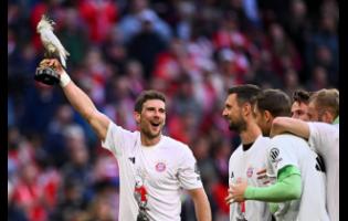 Bayern’s Leon Goretzka (lef) holds a cockatoo trophy as he celebrates after winning the German championship at the end of the Bundesliga  match between Bayern and Stuttgart in Munich, Germany yesterday.