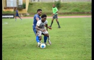 Kimarley Scott of Cavalier FC (front) is tackled by Andrew Vanzie of Spanish Town Police FC during the Jamaica Premier League football match at Stadium East on Monday. Cavalier won 3-0.
