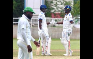 Barbados Pride batsmen Kevin Wickham (centre) and Kraigg Brathwaite meet mid-pitch during their century stand against the Jamaica Scorpions on day three of their West Indies Championship match at Sabina Park yesterday. Jamaica Scorpions’ Kirk McKenzie is in the foreground.