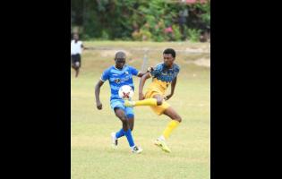 Tyrone Mullings of Racing United FC (right) kicks the ball while Michael Odupe of Molynes United FC (left) reacts during the Jamaica Premier League football fixture at Ferdi Neita Park in Portmore, St Catherine, on Wednesday.