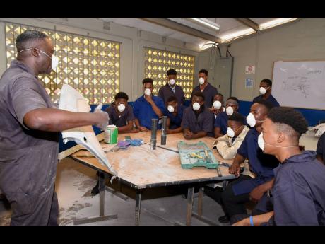 Auto body repair instructor Fitzgerald Thompson (left) conducts a class. 