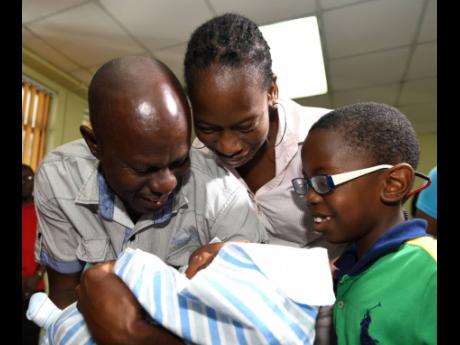 Ricardo Makyn/Chief Photo Editor
Sinclair Hutton (left) holds his son Sae'breon while his partner Suzett Whyte and their other son Rudean look on lovingly. Sae'breon was reunited with his family at the Denham Town police station today, minutes after he was brought in by the Child Protection and Family Services Agency.