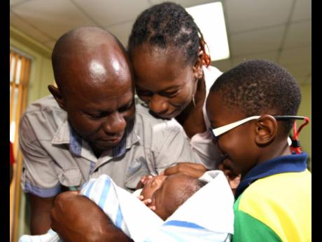 Ricardo Makyn/Chief Photo Editor
Sinclair Hutton caresses his son Sae’breon alongside the child’s mother, Suzett Whyte, and brother, Rudean, at the Denham Town Police Station minutes after he was returned to his family by the Child Protection and Family Services Agency last Friday.