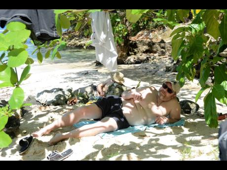 A tourist relaxes in the shade at Winnifred beach in Portland.